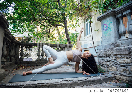 Happy young woman sitting outdoors in yoga position 108798895