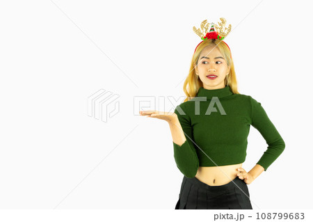 young asian woman wears a reindeer headband for christmas concept poiting hand isolated on white background 108799683