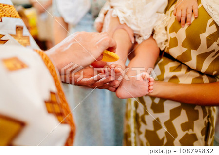 without a face. The priest makes the anointing of the baby's feet.  108799832