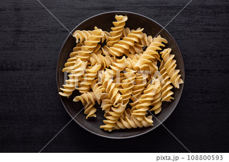 Uncooked fusilli pasta. Uncooked italian pasta on plate. Top view. 108800593