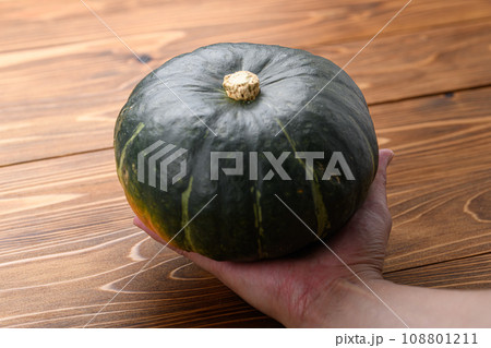 手で持ったかぼちゃ 木目背景 108801211