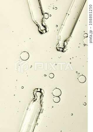 Three pipettes and a serum texture for skin with bubbles. Liquid body care product. Close-up. Three pipettes and a serum texture for skin with bubbles. Liquid body care product. Close-up. 108801250