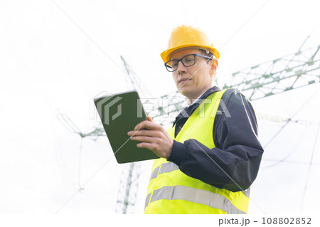 Engineer with digital tablet on a background of power line tower 108802852