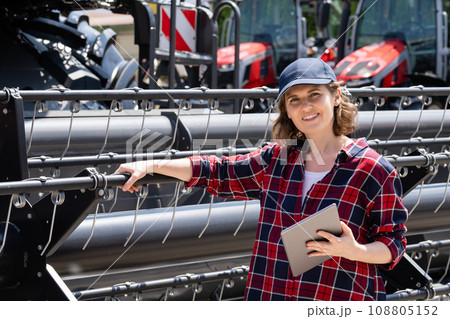 Woman farmer with digital tablet on a background of harvester. Smart farming concept 108805152
