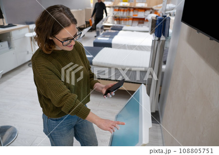 Woman with phone uses self-service kiosk in the shopping mall 108805751
