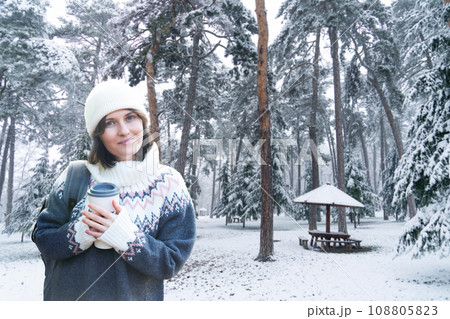 Woman with a cup of hot drink on winter snowy background 108805823