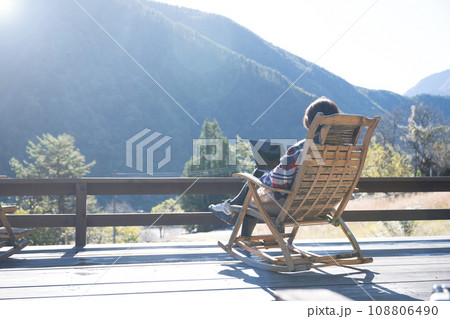 田舎のウッドデッキでリモートワークをする女性の秋冬 カメラ目線の広角の顔無し 田舎のウッドデッキでリモートワークをする女性の秋冬 カメラ目線の広角の顔無し 108806490