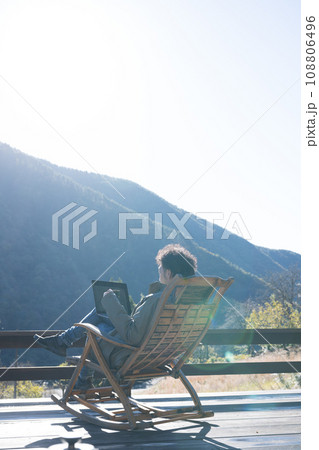 山の見える田舎のウッドデッキでリモートワークをするフリーランスっぽい男性の秋冬 山の見える田舎のウッドデッキでリモートワークをするフリーランスっぽい男性の秋冬 108806496