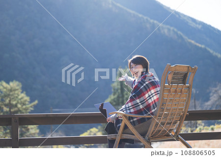 田舎や地方でリモートワークをするフリーランスの女性ウッドデッキにて秋冬の美しい景色を紹介する 108806505