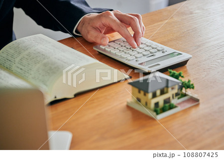 六法全書を見ながら電卓で計算をする男性弁護士 108807425