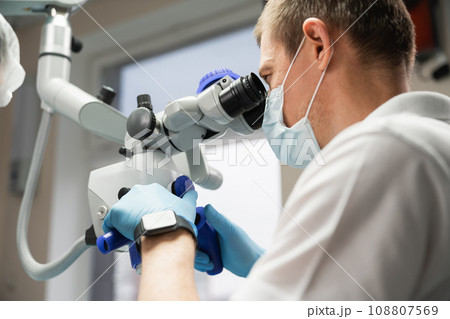 Dentist makes an operation using a dental microscope Dentist makes an operation using a dental microscope 108807569