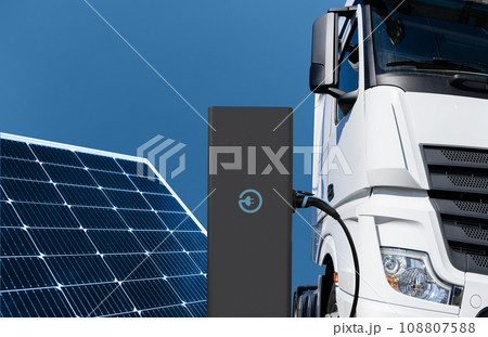 Electric truck with charging station on a background of solar panels Electric truck with charging station on a background of solar panels 108807588