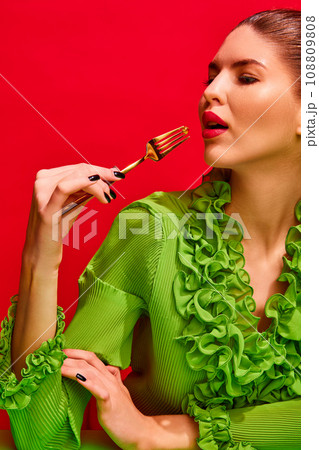 Portrait of elegant, glamour lady sitting at table eating pills, vitamins, tablets from seashell like oyster isolated red background. Portrait of elegant, glamour lady sitting at table eating pills, vitamins, tablets from seashell like oyster isolated red background. 108809808