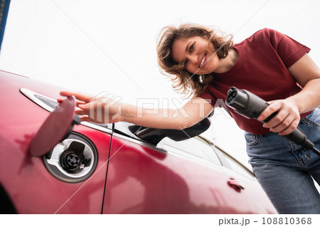 Woman charging red electric car. Woman charging red electric car. 108810368