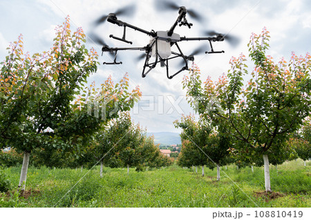 Drone sprayer flies over apple trees. Drone sprayer flies over apple trees. 108810419