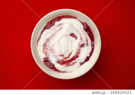 Bowl of yogurt with berry jam swirl on red background, top view 108810521