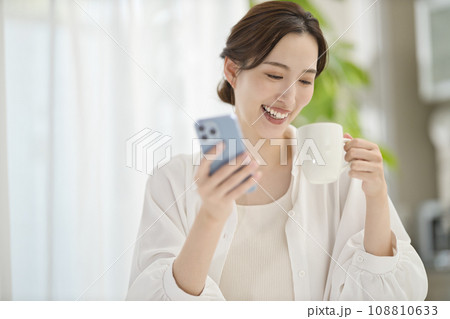 リビングでスマホを見る女性 108810633