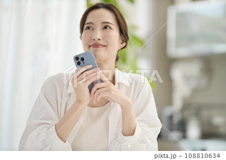 リビングでスマホを見る女性 108810634