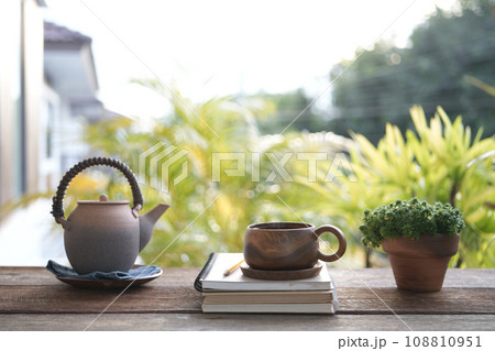 Brown tea cup and tea pot with brown plant pot and notebooks 108810951