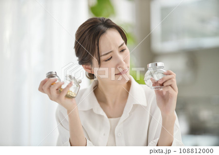 リビングでサプリメントを飲む女性 リビングでサプリメントを飲む女性 108812000