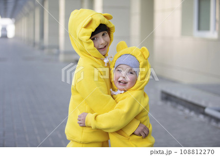 Little brother and sister. Funny children boy and girl in yellow suits hug each other. 108812270