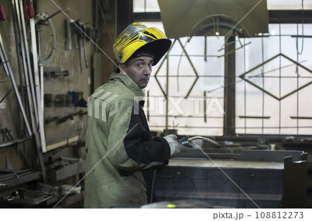 A welder works with metal in a factory shop. 108812273