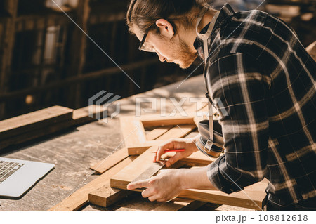 Carpenter Joiner man making wooden furniture in wood workshop professional high skill real authentic handcrafted working people. 108812618