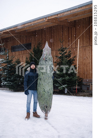 Young man stand by Christmas tree. Big tree for big family. Happy winter holidays 108815295