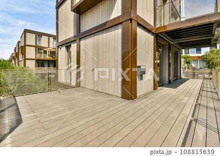 an outside area with wood flooring and metal railings on the side of a house that has been painted white 108815639