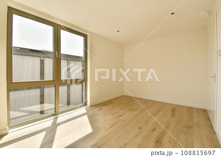an empty room with wood flooring and sliding glass doors that open to the outside, looking out onto the street 108815697