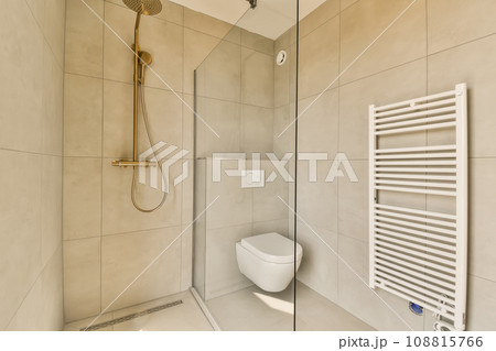 a bathroom with a toilet, shower and towel rack on the wall next to it is a glass enclosed shower door a bathroom with a toilet, shower and towel rack on the wall next to it is a glass enclosed shower door 108815766