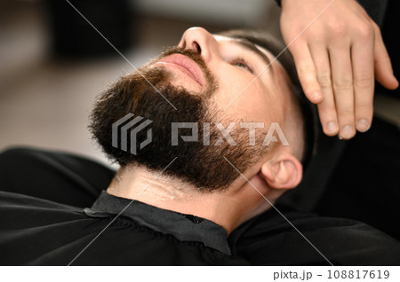 Barber applies shaving gel to the face of a bearded man Barber applies shaving gel to the face of a bearded man 108817619