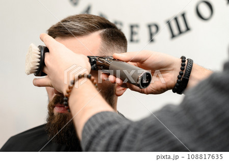 Haircut and alignment of the head contour with a hair clipper trimmer. Short haircut in the barbershop. Haircut and alignment of the head contour with a hair clipper trimmer. Short haircut in the barbershop. 108817635