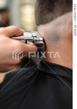 Barber shaves the temple with cordless trimmer during a short haircut on the sides of the head. 108817643