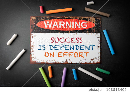 Success is Dependent on Effort. Metal warning sign and colored pieces of chalk on a dark chalkboard 108818403