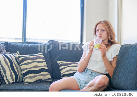 ソファーに座りマグカップのコーヒーを飲む女性 108818680