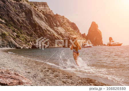 Fitness woman sea. Happy middle-aged woman in blue sportswear running on the beach, promoting a female fitness pilates yoga routine concept. Healthy lifestyle. 108820380