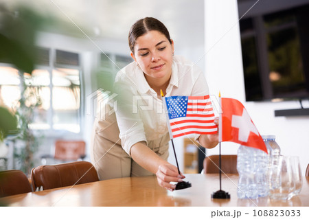female assistant prepares conference room for diplomats of Switzerland and USA female assistant prepares conference room for diplomats of Switzerland and USA 108823033