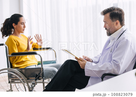 Psychiatrist doctor collect data talk with patient on wheelchair for mental care health problems check followup in hospital clinic 108823079