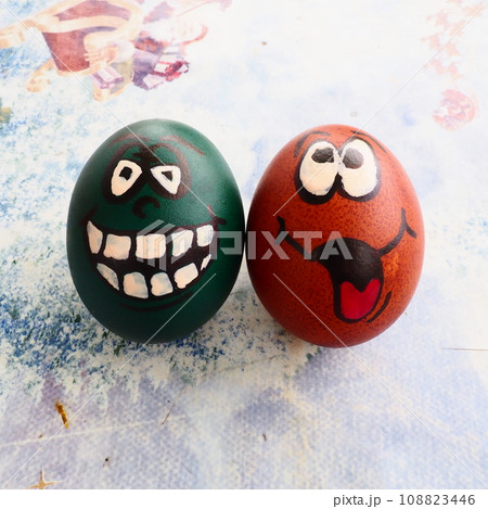 Easter eggs dyed green and brown with painted laughing faces. Funny grimaces with eyes, tongue and big white teeth. Scary face for Halloween. Emoticon for Easter. Light abstract background. Easter eggs dyed green and brown with painted laughing faces. Funny grimaces with eyes, tongue and big white teeth. Scary face for Halloween. Emoticon for Easter. Light abstract background. 108823446