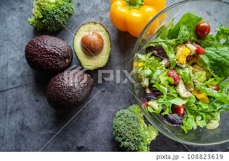 Glass bowl with fresh salad, greens, avocado and vegetables. Healthy food concept. Rustic style, top view Glass bowl with fresh salad, greens, avocado and vegetables. Healthy food concept. Rustic style, top view 108823619