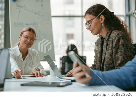 Businesspeople working together in modern coworking sitting at desk. Teamwork concept Businesspeople working together in modern coworking sitting at desk. Teamwork concept 108825920