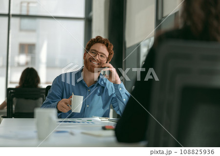 Businessman talking phone with client while sitting in modern office and drink coffee 108825936