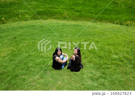Asian Couple sexy woman in black shirt with jean and dress sitting on grass field on mountain in summer season. 108827623