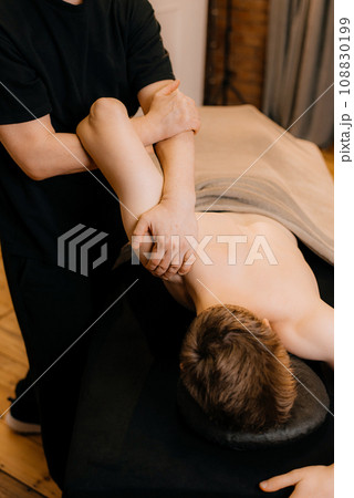 Physiotherapist massaging male patient with injured shoulder blade muscle. Sports injury treatment. 108830199