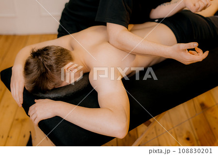 Physiotherapist massaging male patient with injured shoulder blade muscle. Sports injury treatment. 108830201