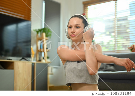 Attractive young sportswoman in headphone stretching exercises at home Attractive young sportswoman in headphone stretching exercises at home 108831194