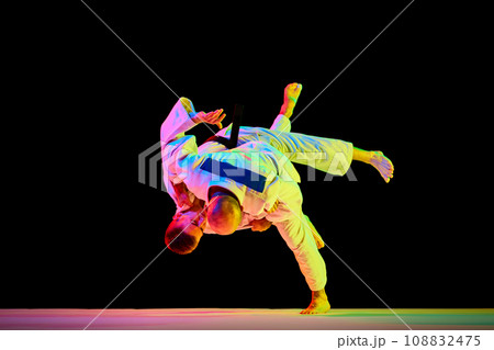 Two young man professional judoist fighting, performing technical skill in neon light isolated black studio background. Copy space for ad, text 108832475