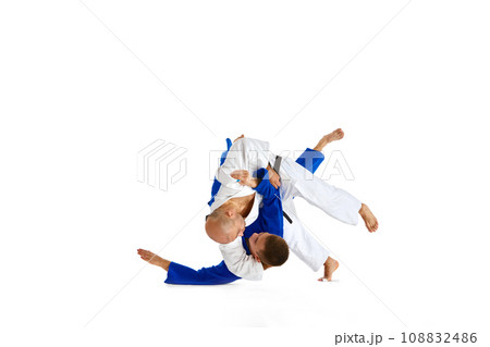 Two male professional sportsmen during match. Karate fighter attacking his opponent with leg technique isolated white background. 108832486