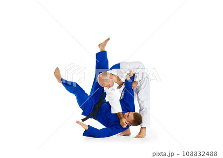Martial arts match. Two professional karate fighters, sportsmen in uniform performing kicks during competition isolated white background. 108832488